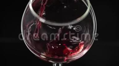 玫瑰酒。 红酒倒在黑色背景上的酒杯里。 慢动作